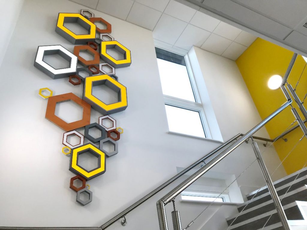 Hexagonal sign branding adorning an internal wall up a staircase in the Telford Mann office building